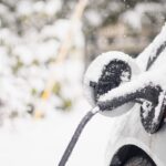 An electric vehicle charges in the snow.