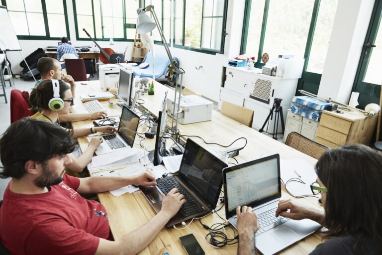 Group of male and female programmers coding in a big room.